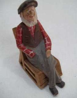   wood hand carving of old man in a rocking chair. Figurine is painted